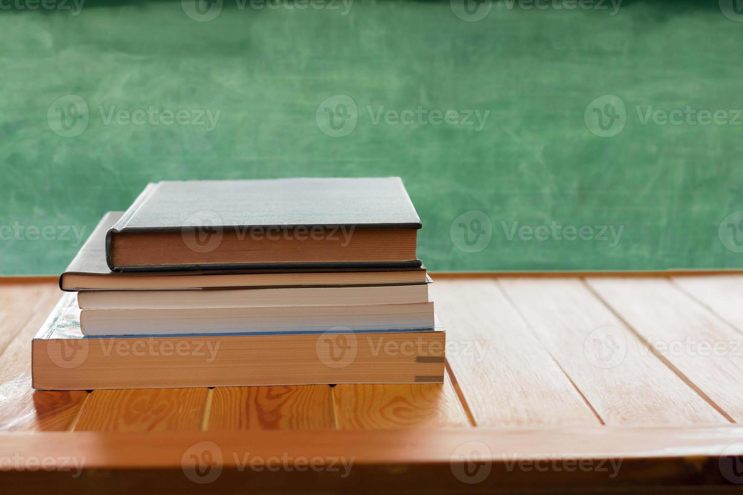 libros de texto sobre una mesa de madera frente a una pizarra borrosa foto