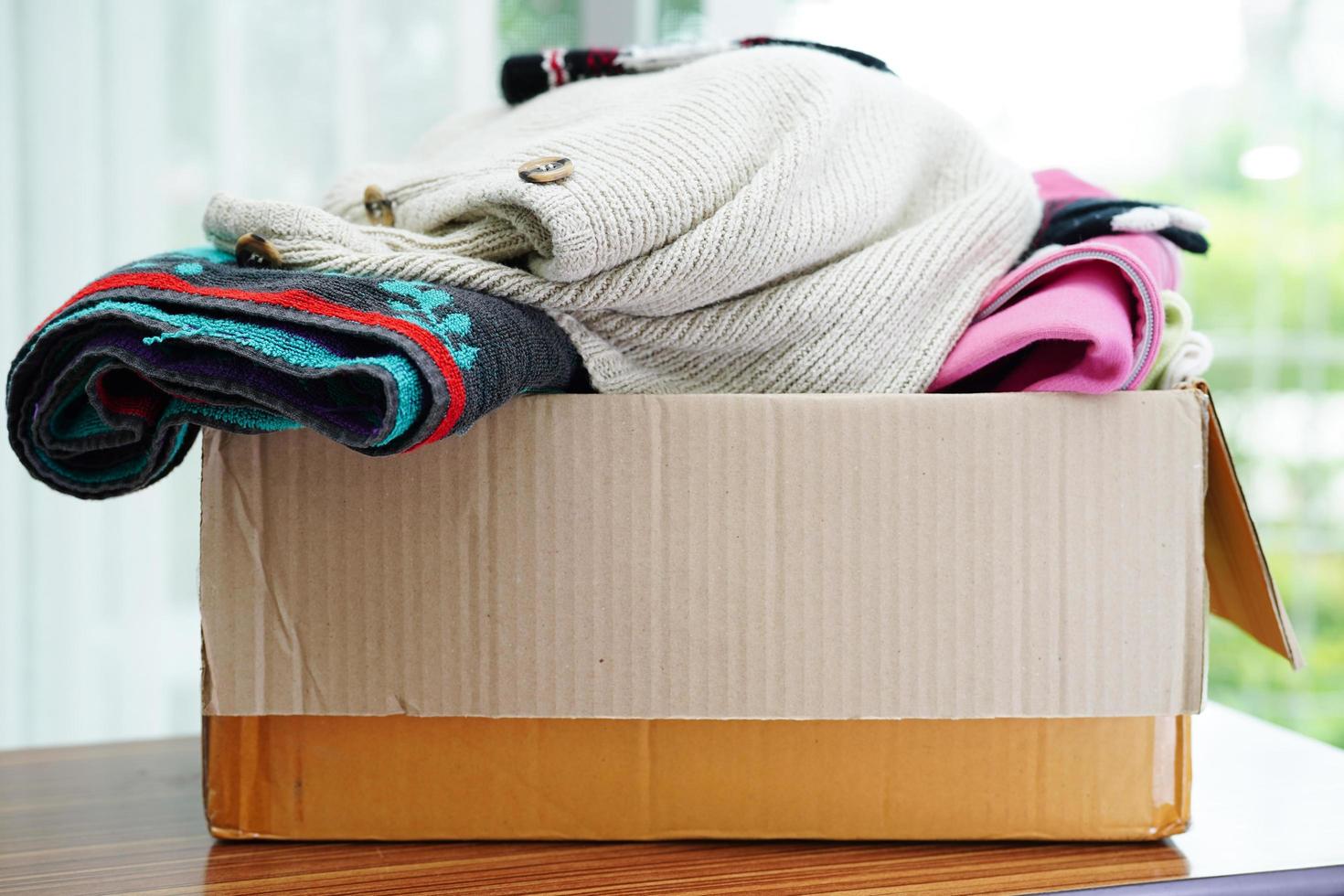 Clothes donations in cardboard box for volunteer. photo