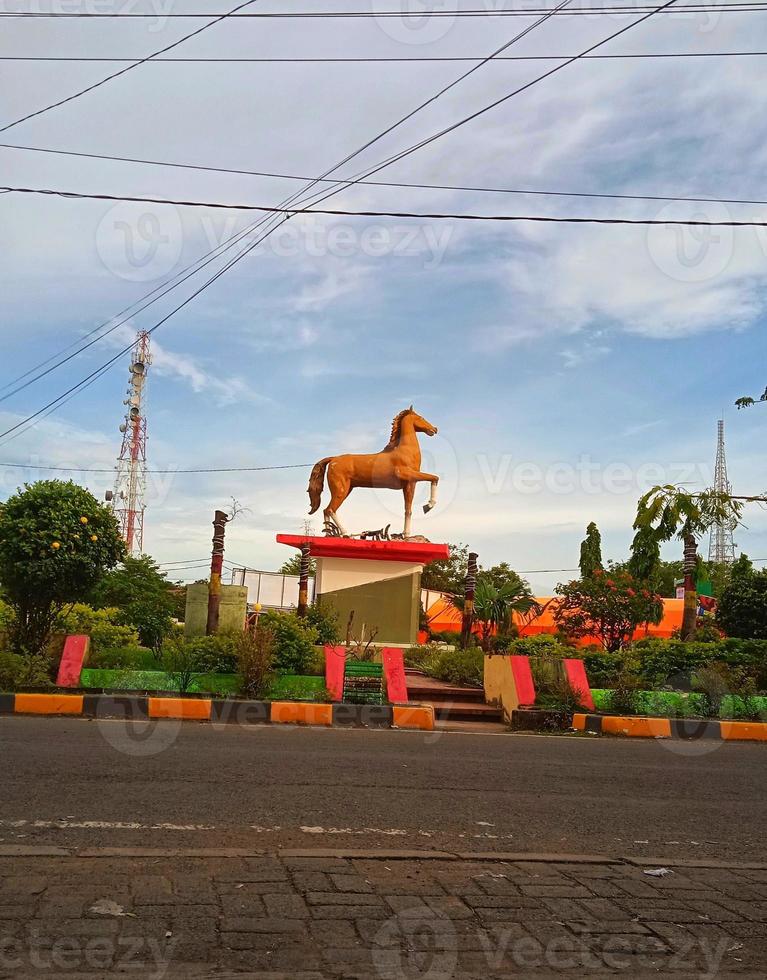 horse statue in flower garden location with sky blue background and white clouds photo