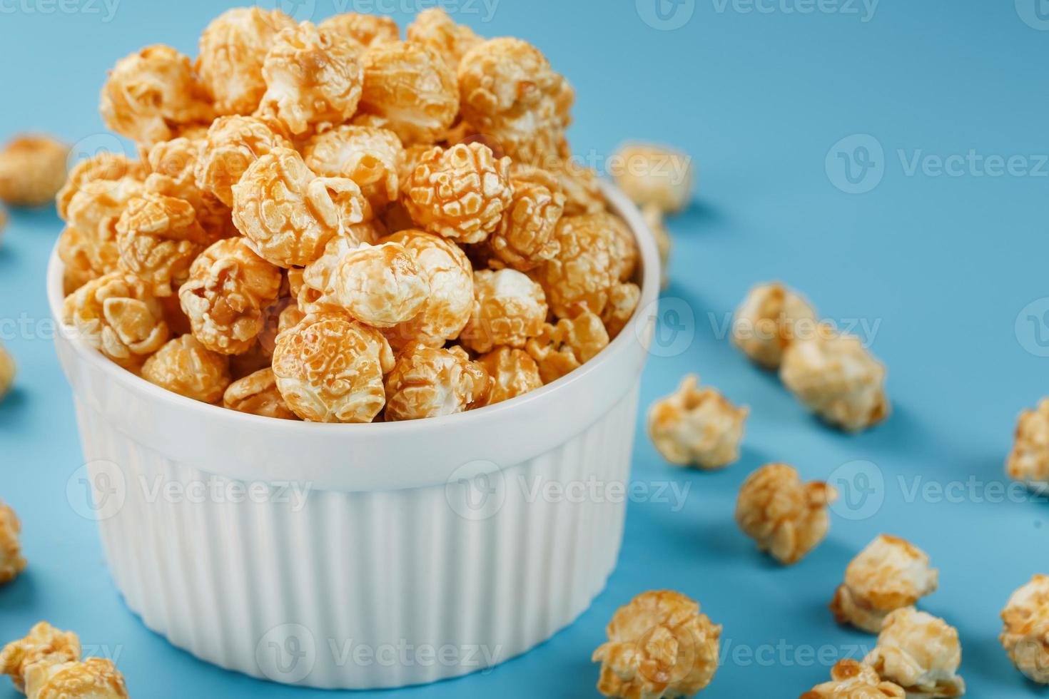 Caramel of the popcon in a white cup with a scissor on a blue background. photo