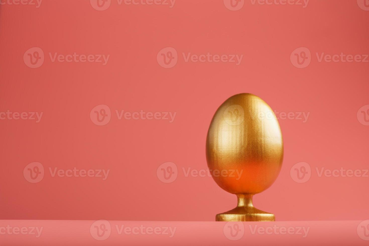 Golden egg on a pink background with a minimalistic concept. Space for text. Easter egg design templates. Stylish decor with minimal concept. photo