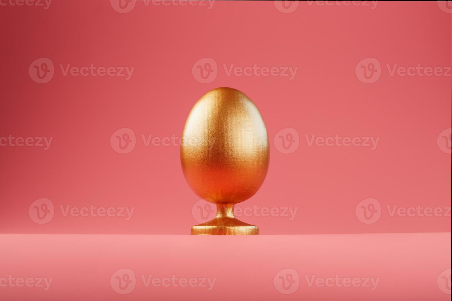 Golden egg on a pink background with a minimalistic concept. photo