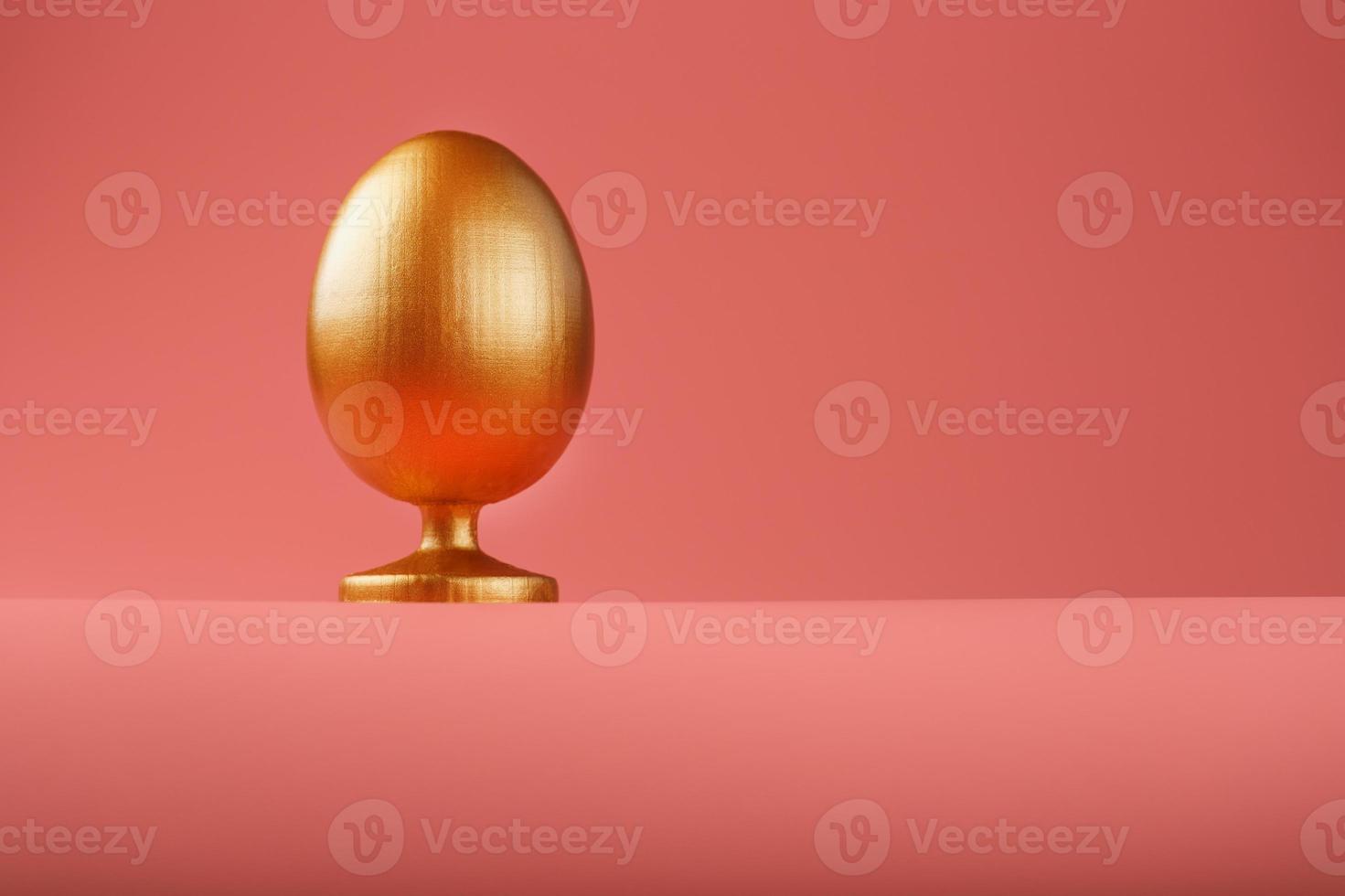 Golden egg on a pink background with a minimalistic concept. Space for text. Easter egg design templates. Stylish decor with minimal concept. photo