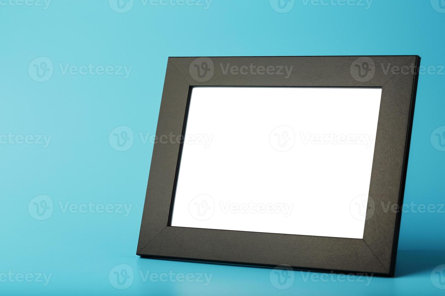 Black photo frame with empty space on a blue background.