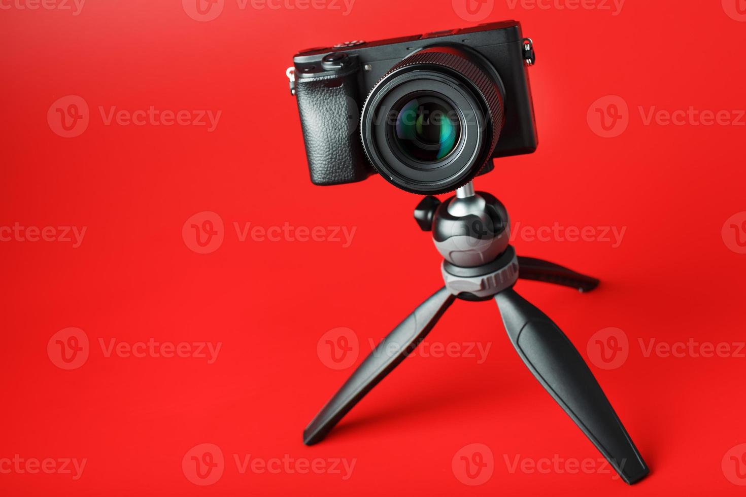 Professional camera on a tripod, on a red background. Record videos and photos for your blog, reportage