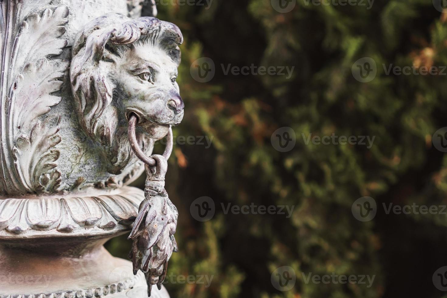 cabeza de león de bronce hecha de metal en una columna en el parque. foto