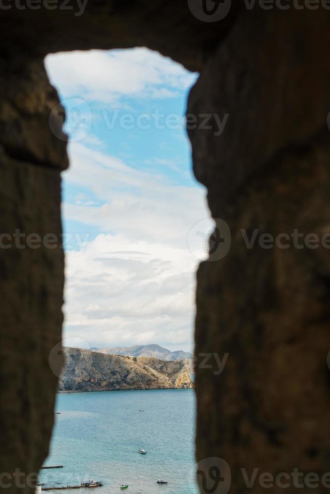 View of the sea coast through the window in the fortress. photo