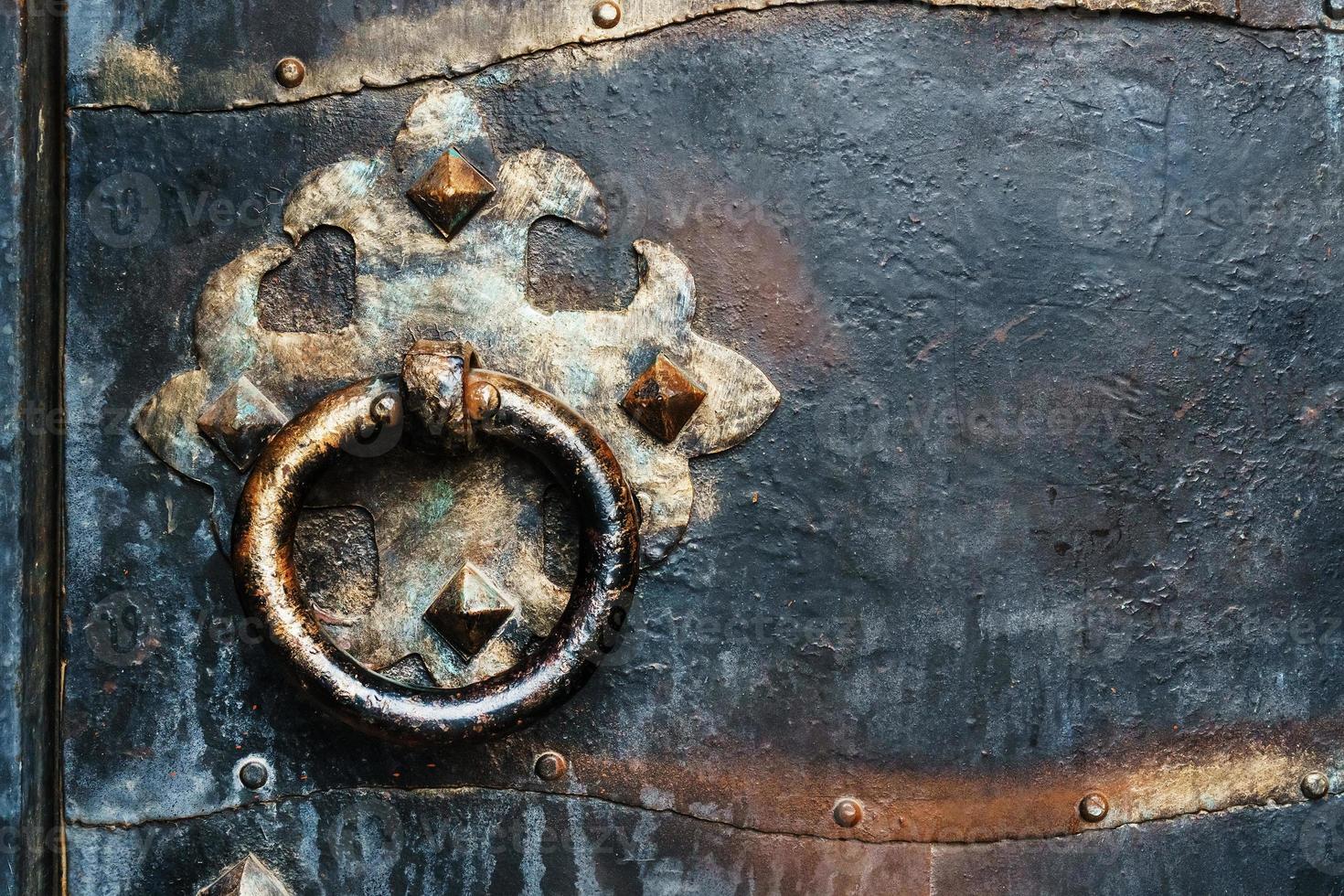 Steel black door of an ancient castle with a round vintage handle. photo