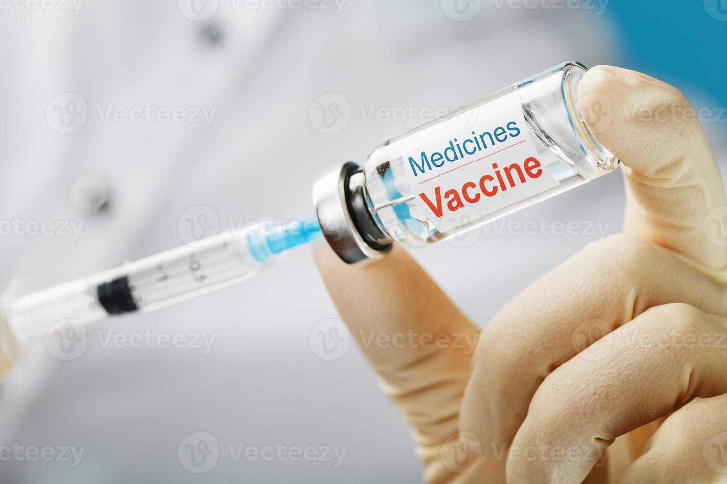 The doctor holds with protective gloves and a mask holds the Ampoule with the vaccine. photo