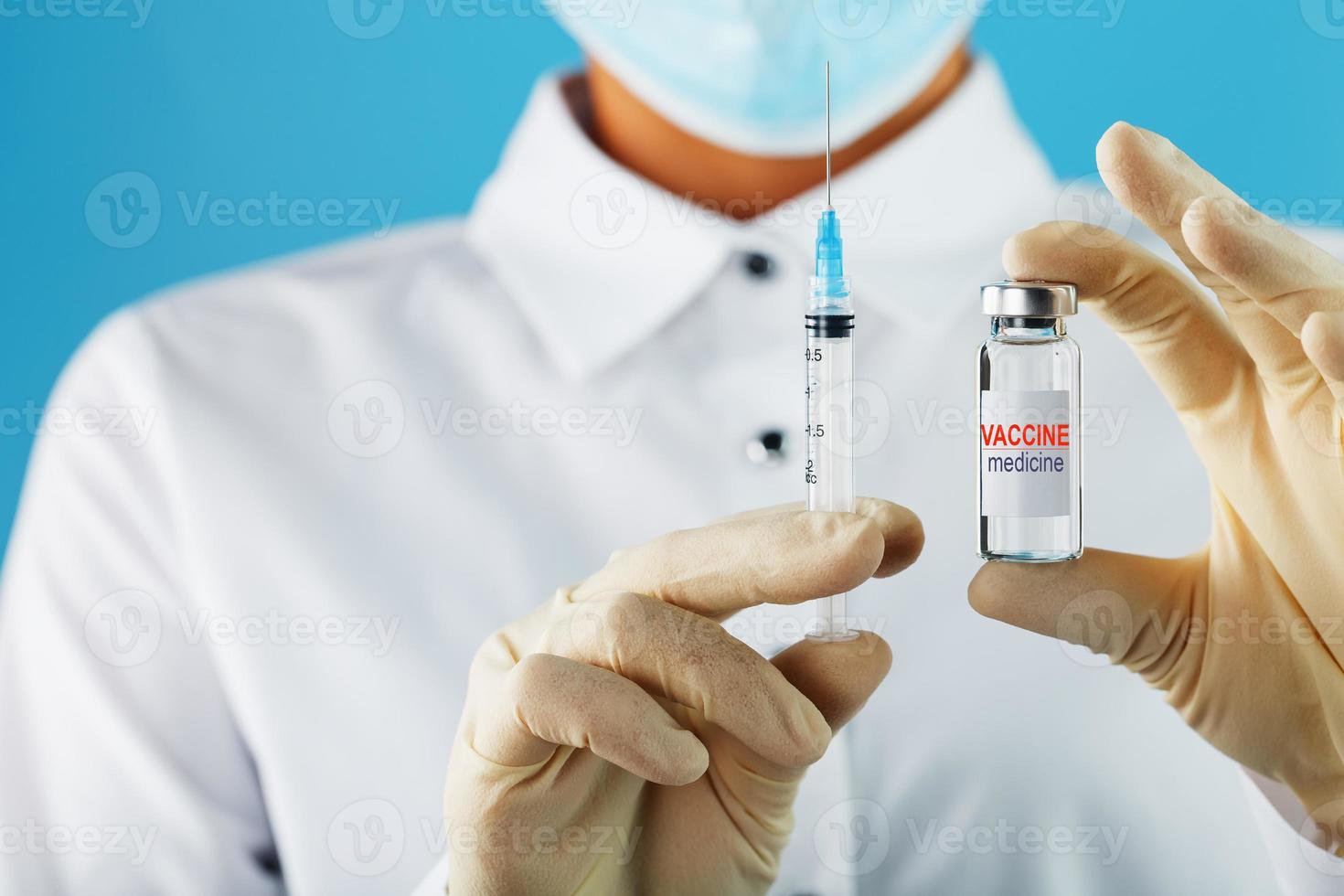 el médico sostiene con guantes protectores y una máscara sostiene la ampolla con la vacuna. foto