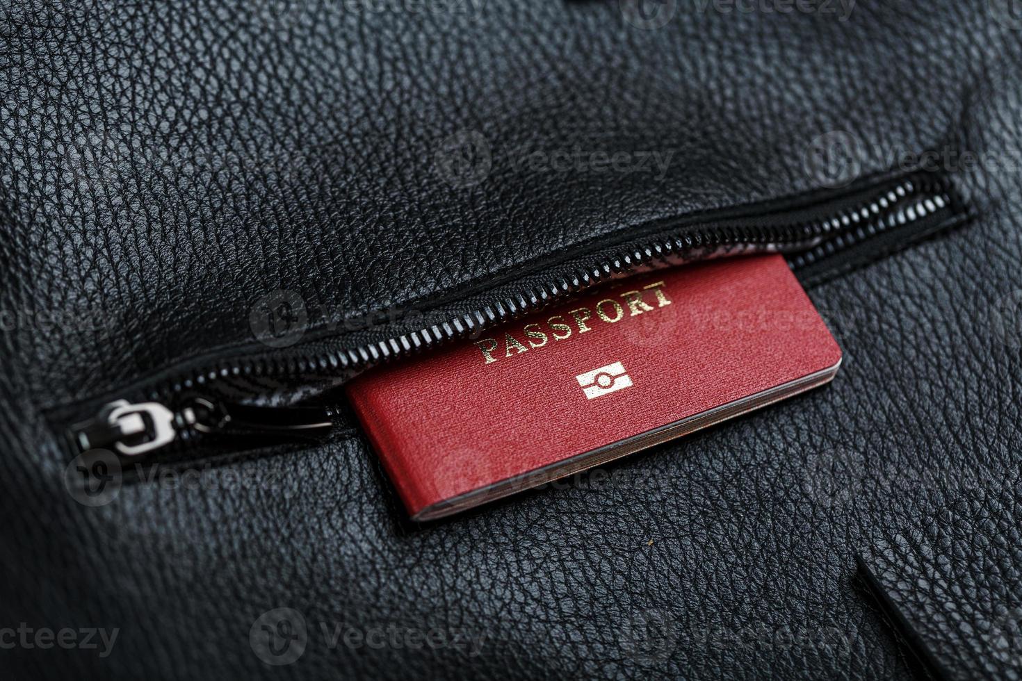 el pasaporte se ve fuera del bolsillo de un bolso de cuero negro, macro hecho a mano, materiales naturales. foto