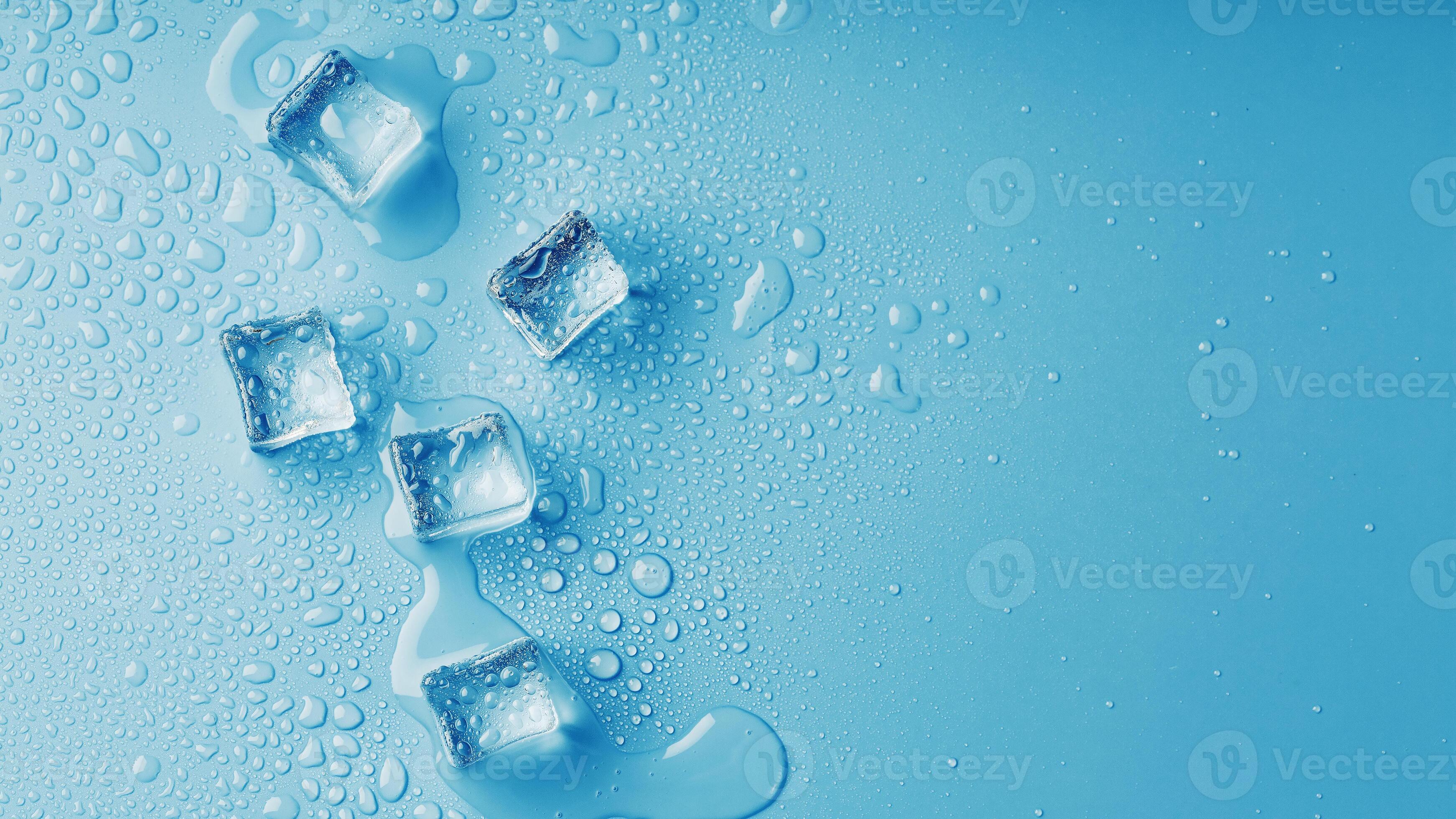 Ice cubes with water drops scattered on a blue background, top view