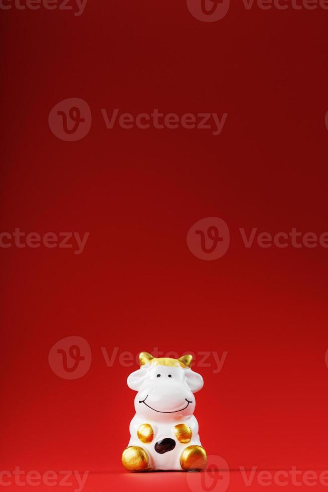 Christmas toy of a cow made of ceramic on a red background. 2021 year of the Bull, cow. New year's symbol photo