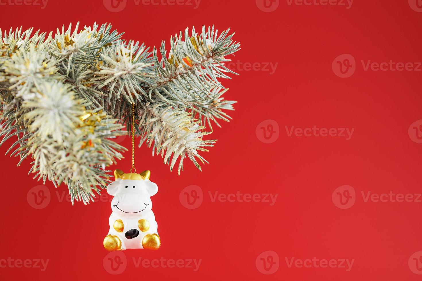 Figure of a Cow on a spruce branch, on a red background. photo