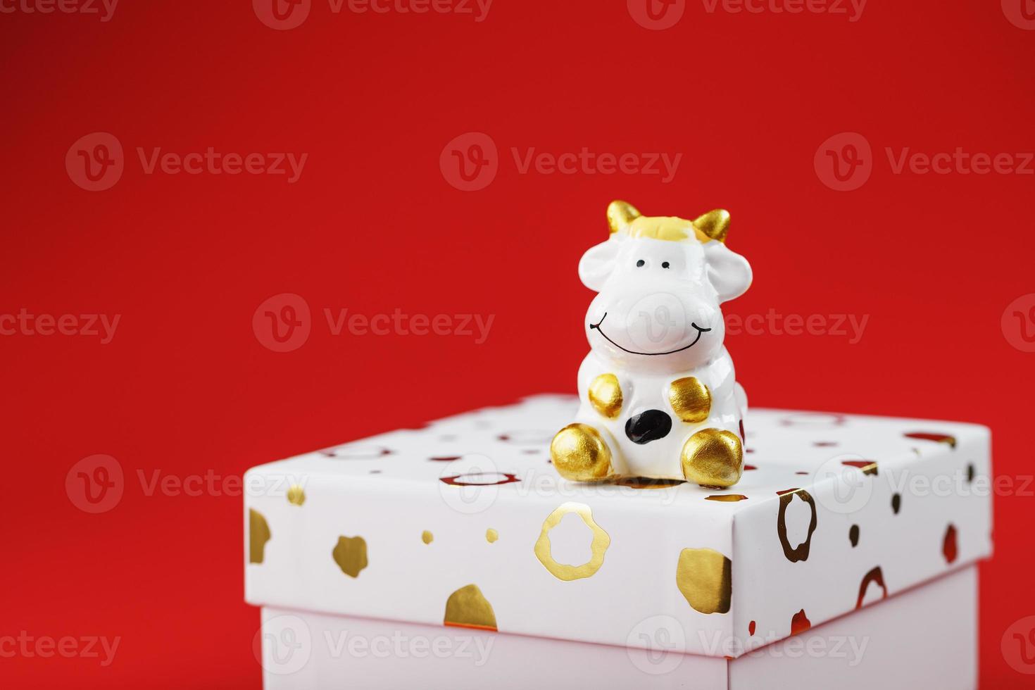 Cow figurine on a gift box on a red background, with free space. photo