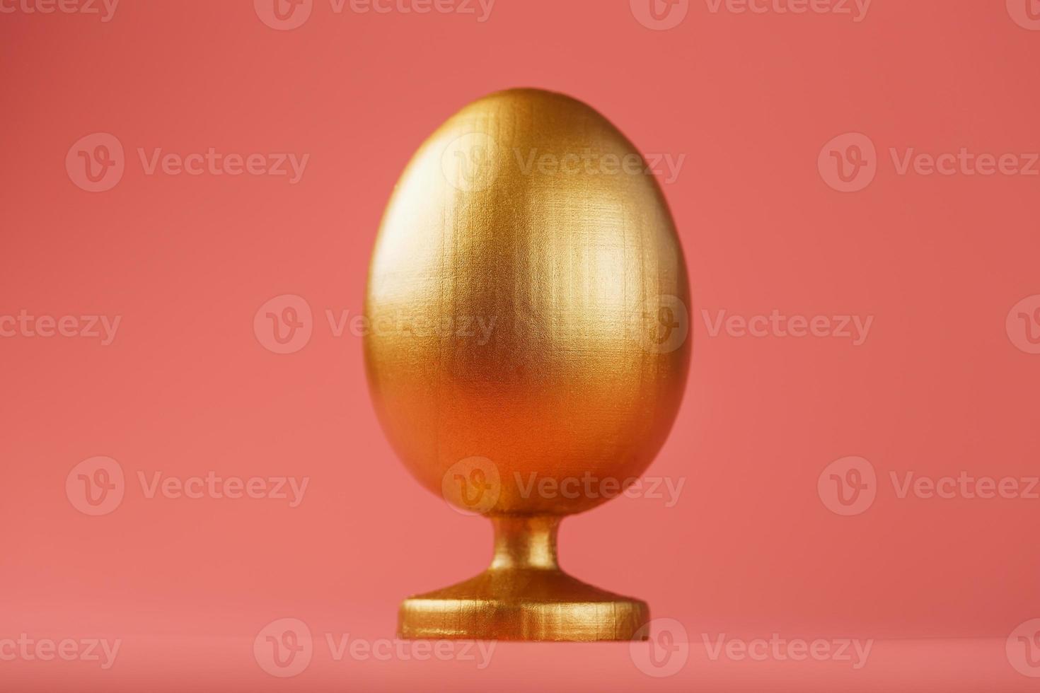 Golden egg on a pink background with a minimalistic concept. Space for text. Easter egg design templates. Stylish decor with minimal concept. photo