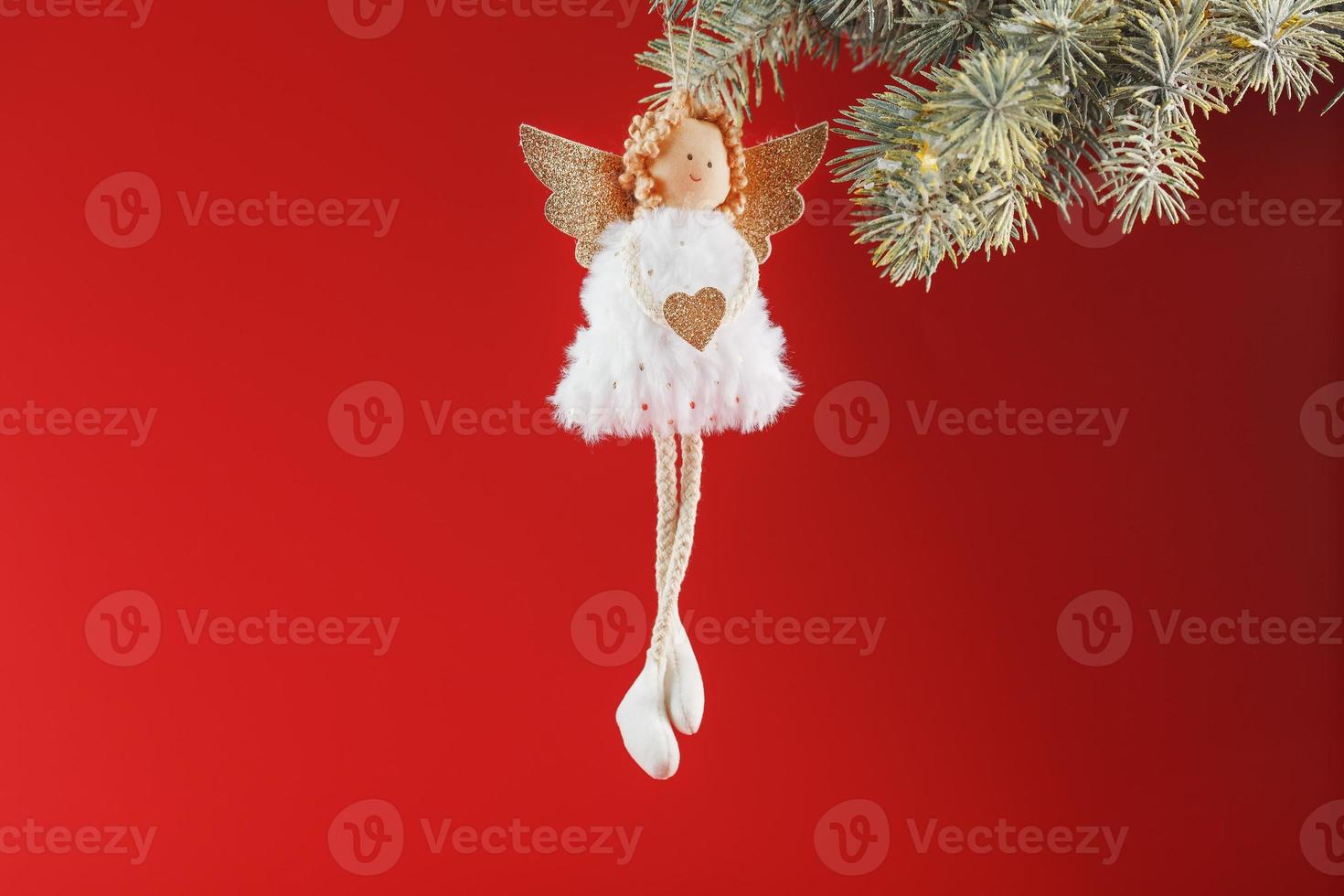 Handmade christmas angel toy on a Christmas tree on a red background. photo