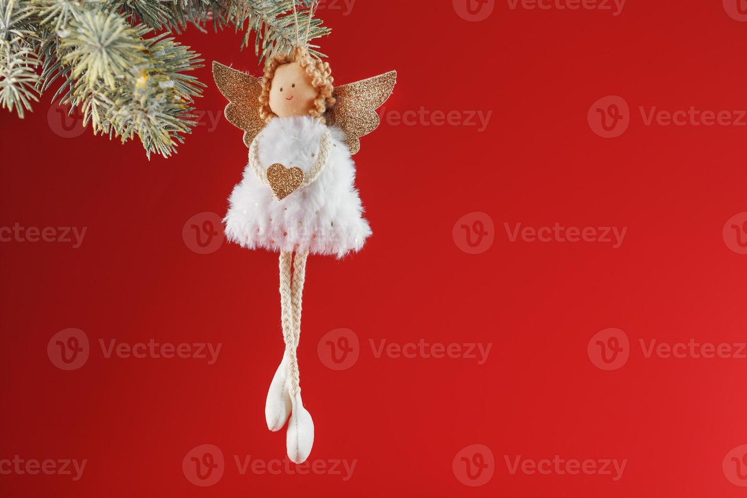 White angel toy on a Christmas tree on a red background. photo