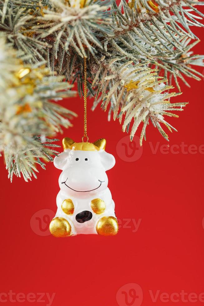 Figure of a Cow on a spruce branch, on a red background. photo