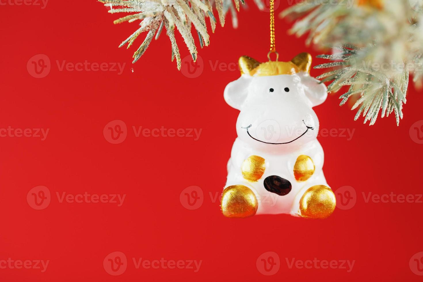 Figure of a Cow on a spruce branch, on a red background. Free space for text. photo