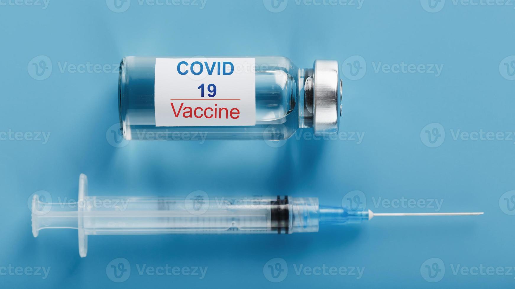 Syringe and ampoule with a vaccine against the Covid-19 virus against diseases on a blue background. photo