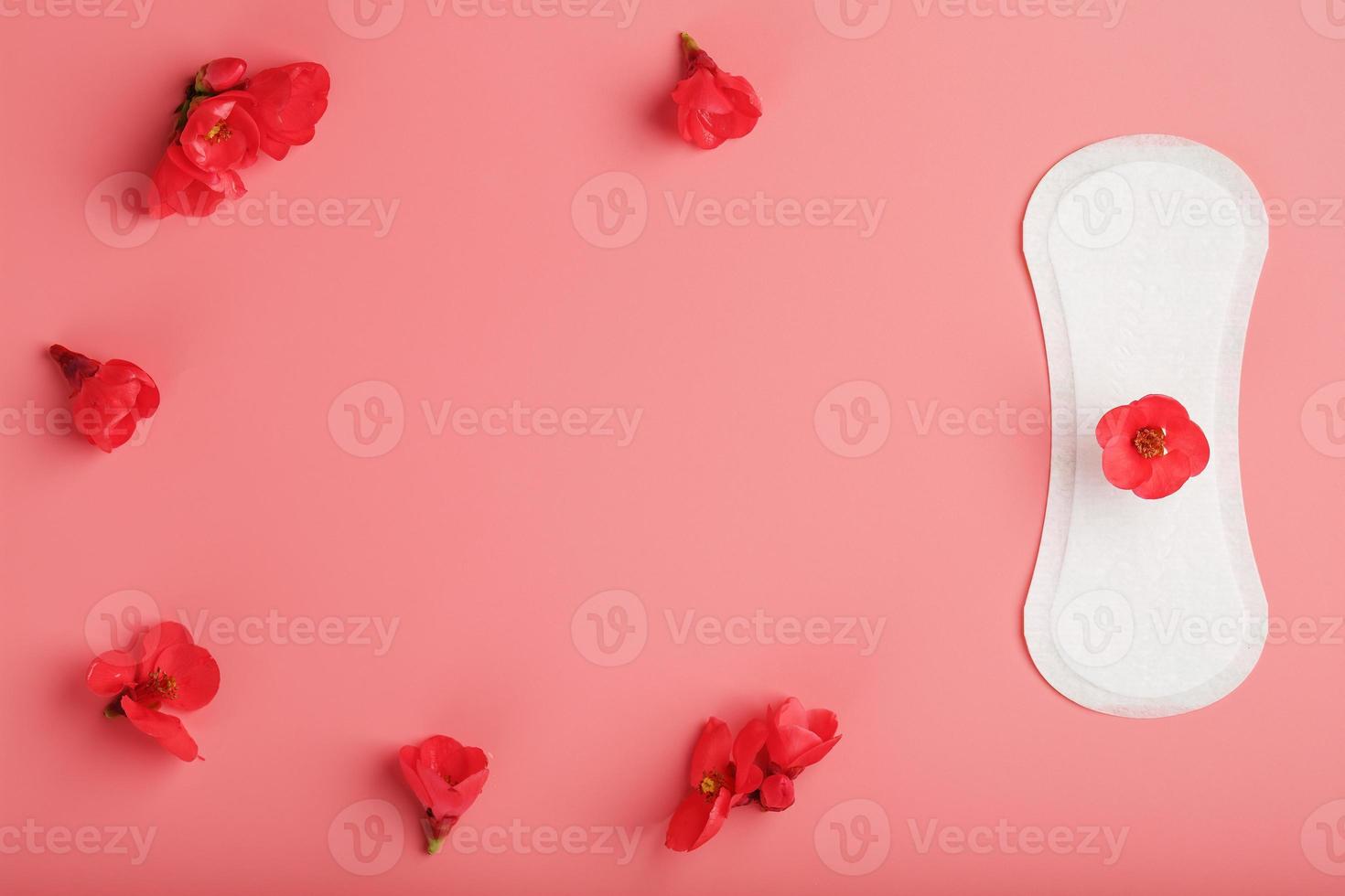 Sanitary pad on a pink background with a red flower on top, with a border of flowers for text and images. Free space. photo