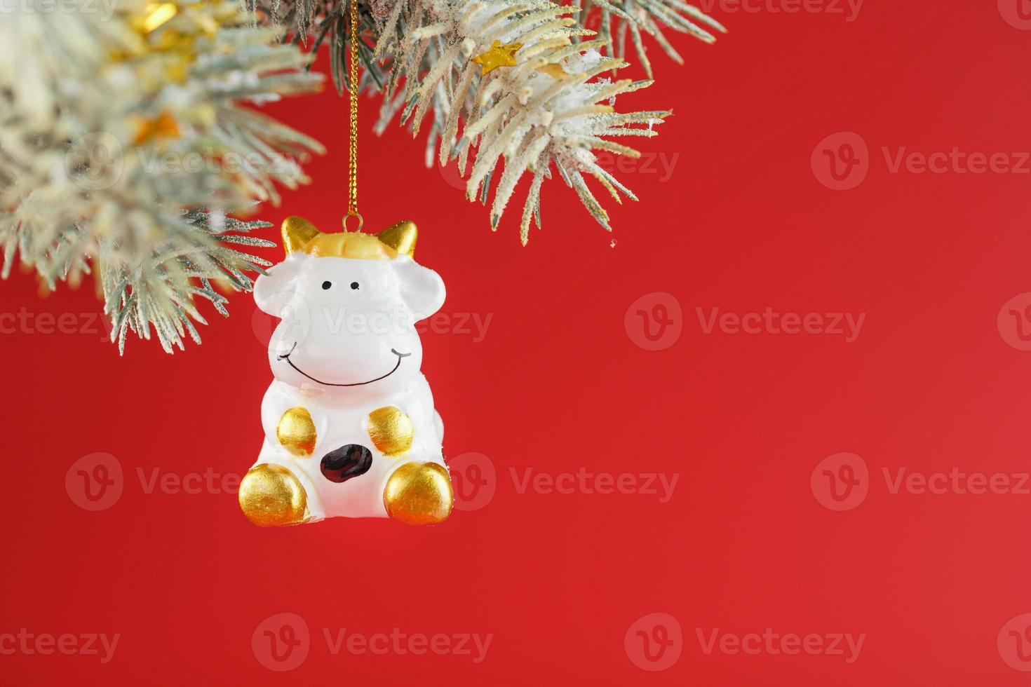 Figure of a Cow on a spruce branch, on a red background. photo