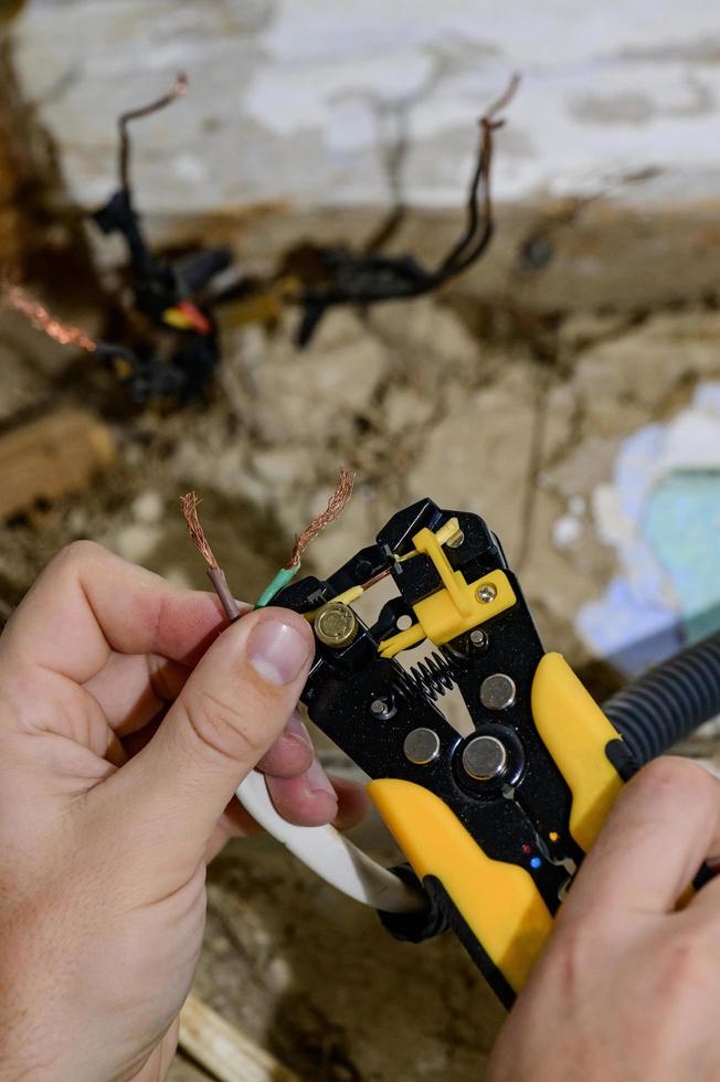 uso de la herramienta para la eliminación del aislamiento para la eliminación del extremo de un cable eléctrico durante la reparación y renovación del cableado eléctrico en una red eléctrica doméstica, trabajos eléctricos. foto