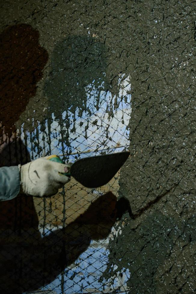 un hombre arroja mortero de hormigón en la pared, la primera capa de yeso en la pared, trabajos de reparación en ucrania. foto