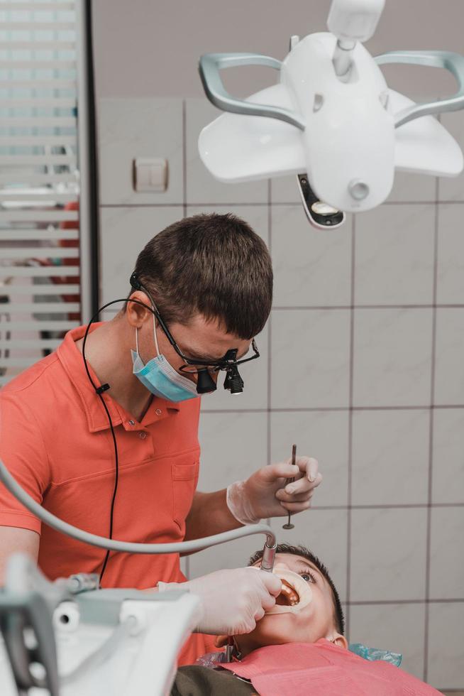 Dental treatment of a child, removal of caries with a drill, open mouth and ejector saliva. photo