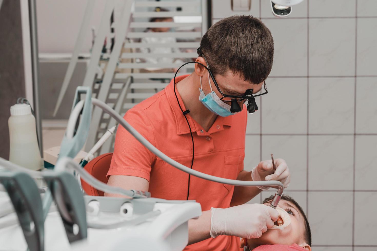 Dental treatment of a child, removal of caries with a drill, open mouth and ejector saliva. photo