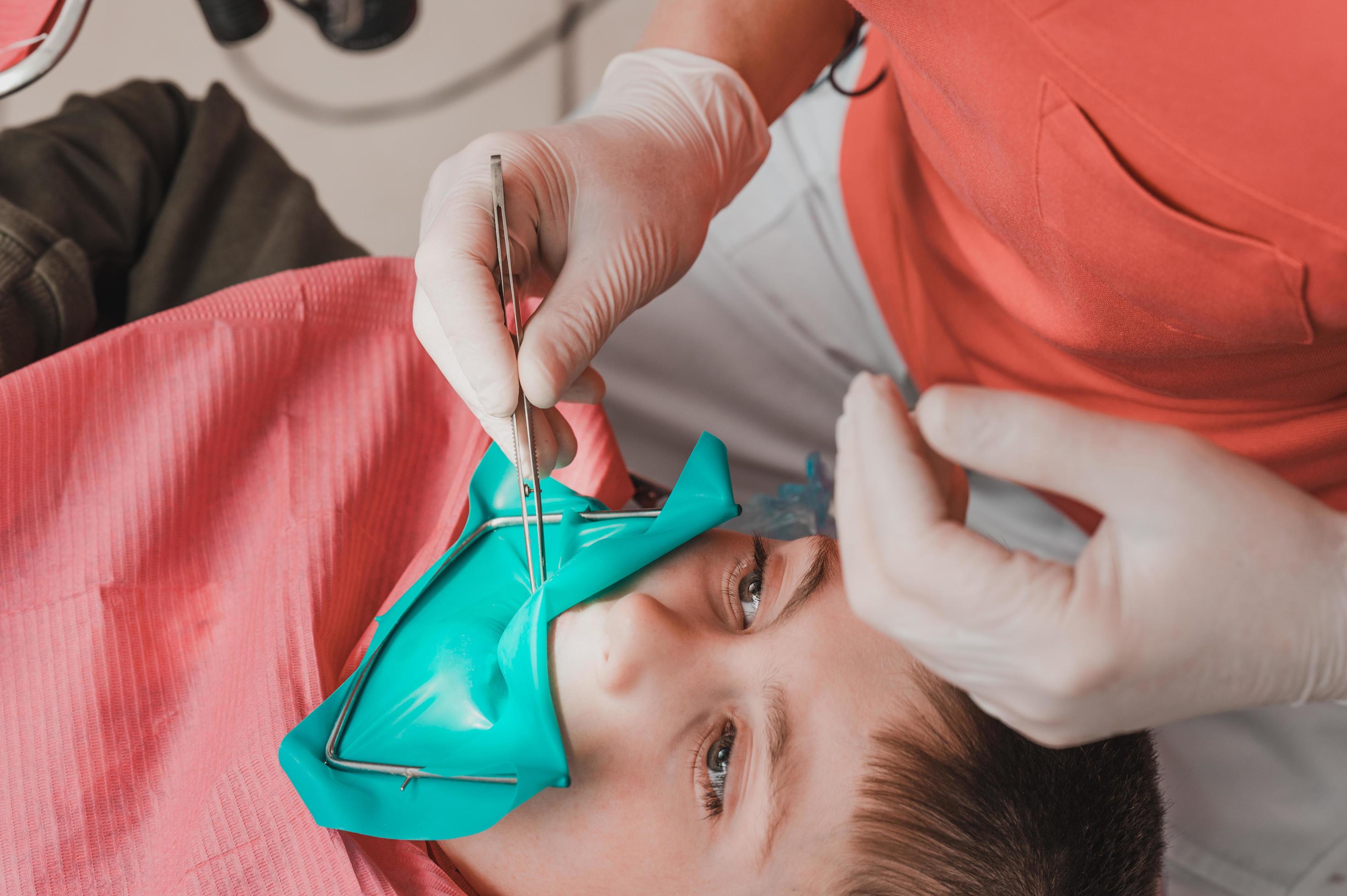 The dentist treats the child's tooth using a rubber dam. 13677526 Stock