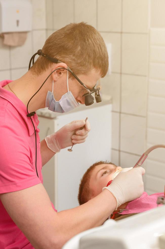 tratamiento dental de un niño, eliminación de caries con un taladro, boca abierta y eyector de saliva. foto