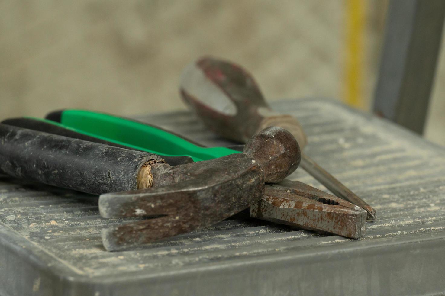 Set of three construction tools on a ladder hammer, pliers and screwdriver. photo