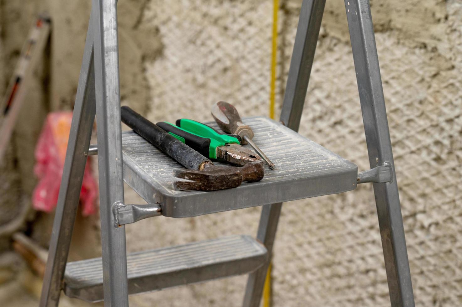 conjunto de tres herramientas de construcción en un martillo de escalera, alicates y destornillador. foto