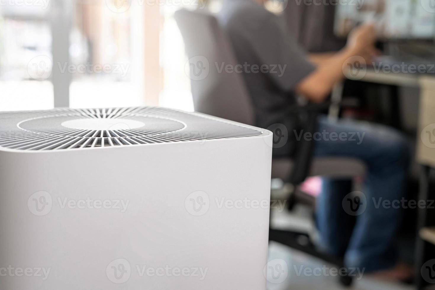 el purificador de aire en la habitación es muy seguro y limpio para respirar con filtro de polvo pm 2.5 y un hombre usa el escritorio de la computadora en casa foto