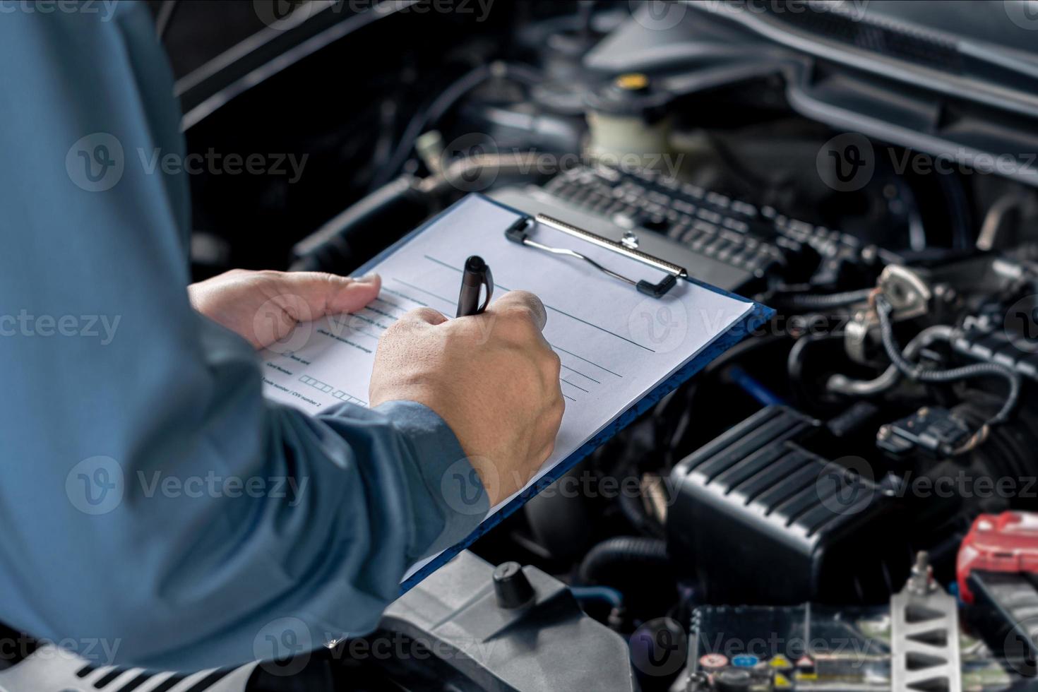 Close up hand car service staff check engine malfunctions and mistake check list in engine room , Car service concept photo