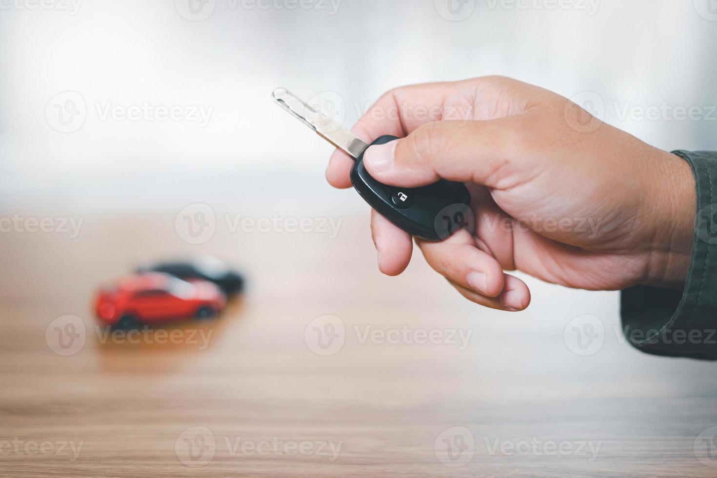 Close up hand of man holding and push remote control for lock and Unlock car , concept model toy a car in blur background photo