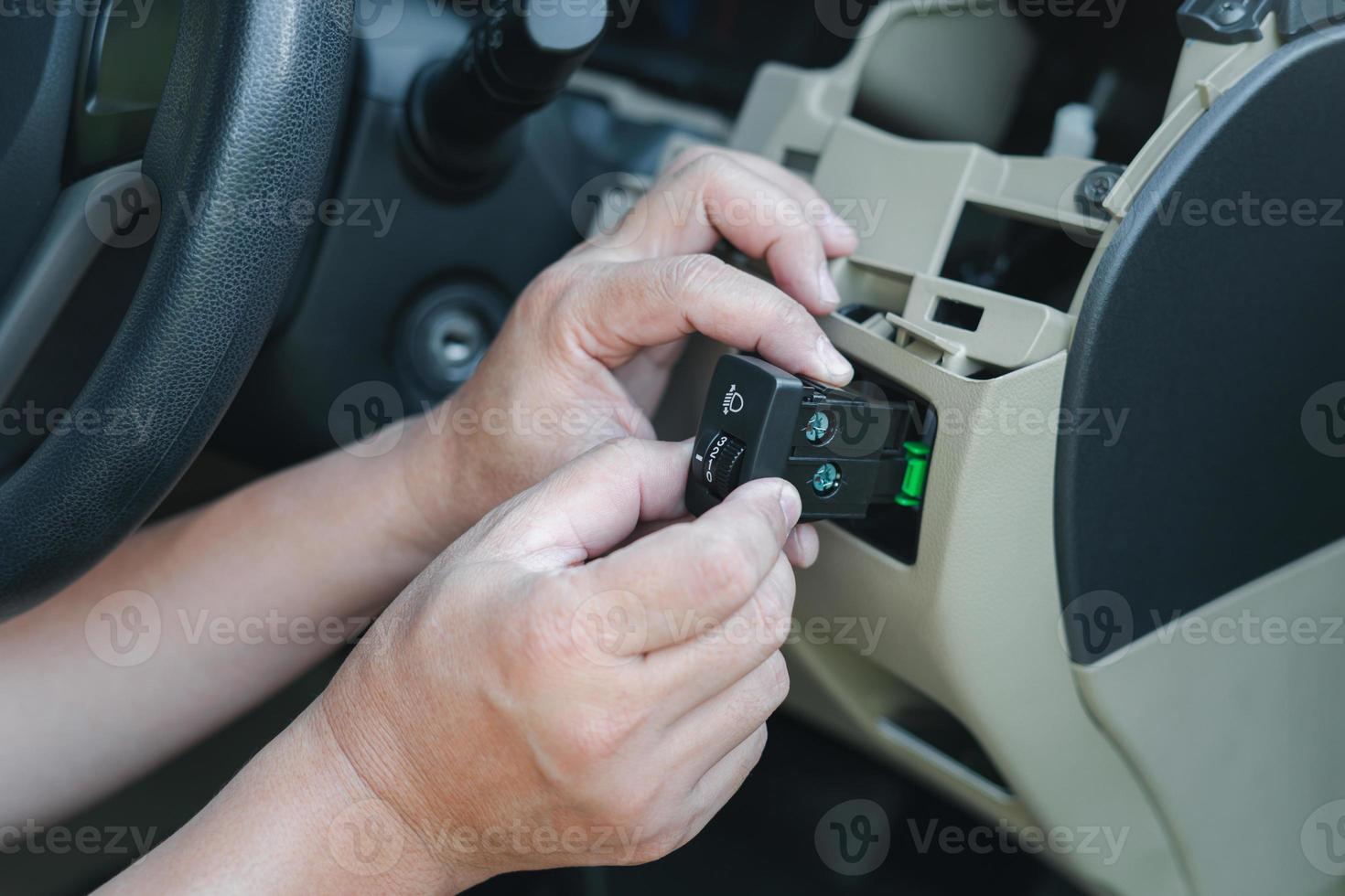 Close up hand Technician checking car headlight switch for maintenance to verify that the spare parts need to be replaced in service shop photo