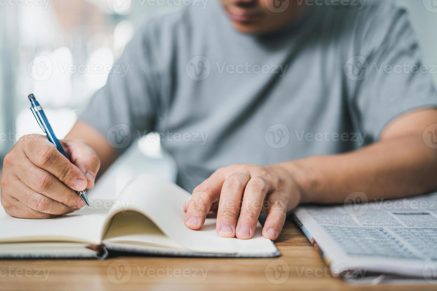 Man looking the newspaper for a new job and use pen write in notebook home while working at home photo