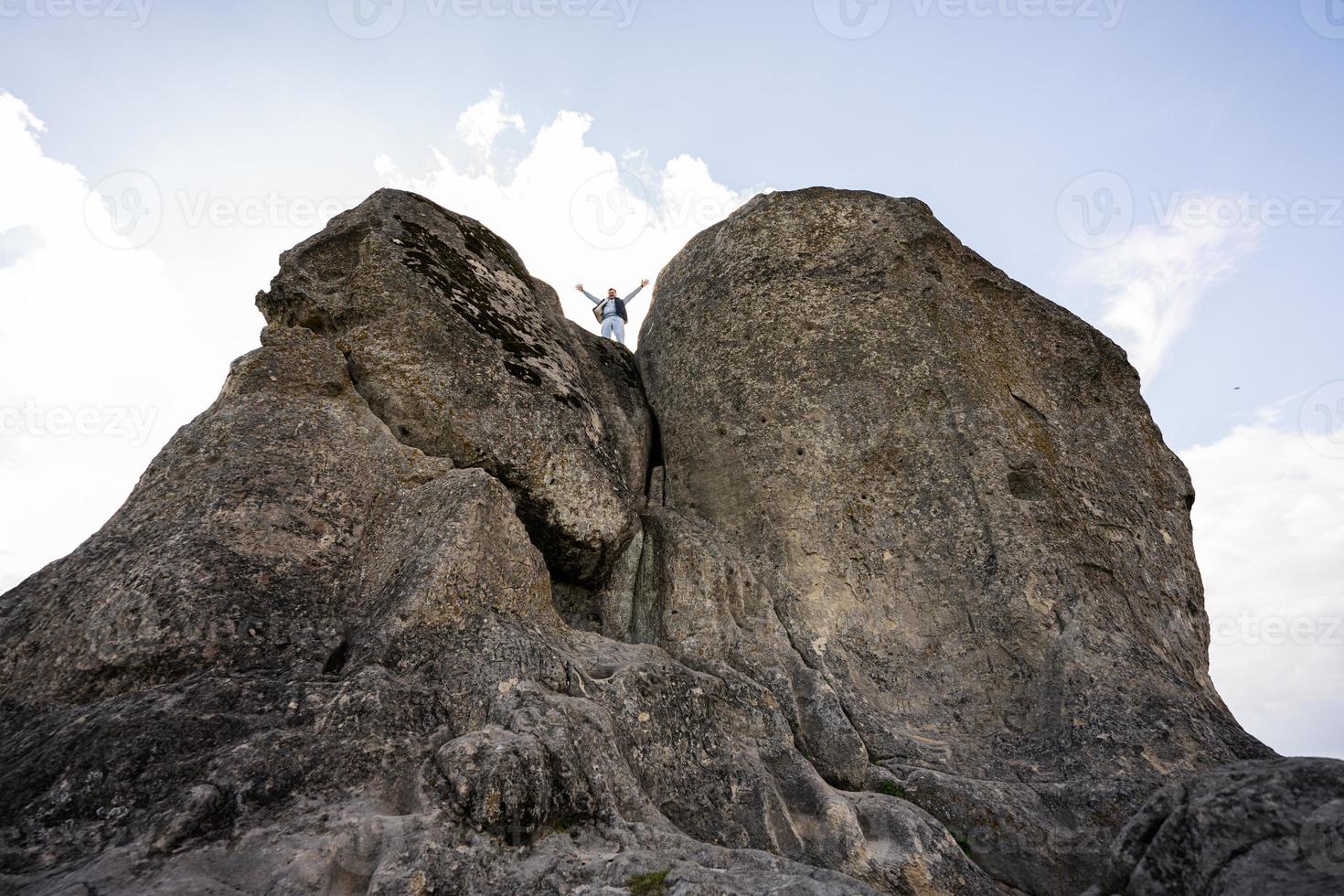 Man climbing on top of big stone in hill. Pidkamin, Ukraine. photo