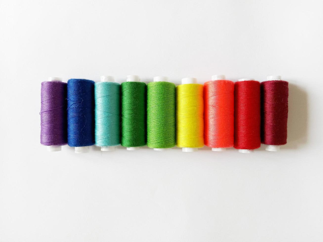 sewing threads arranged in rainbow order on white background photo