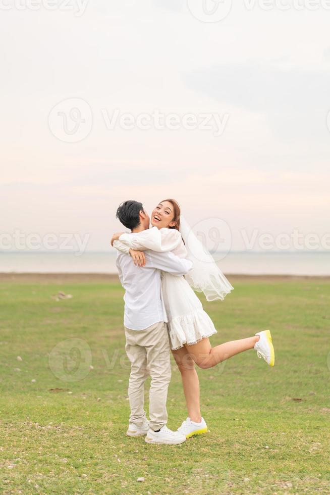 Happy young Asian couple in bride and groom clothing photo