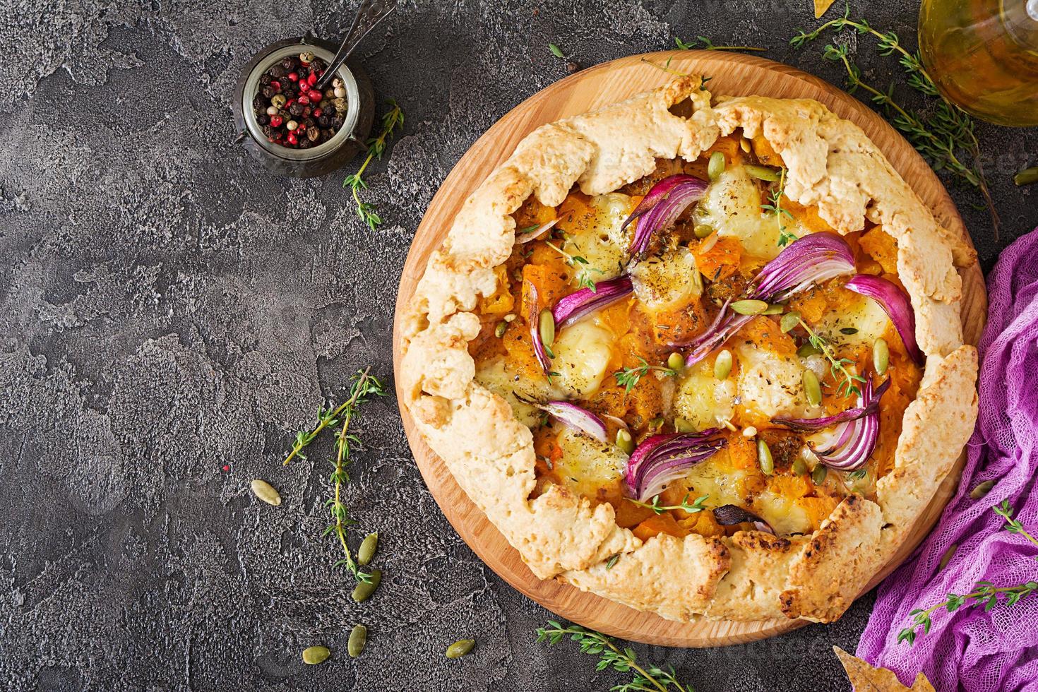 Galette pie with pumpkin and mozzarella cheese on dark background. Thanksgiving day food. Top view. photo