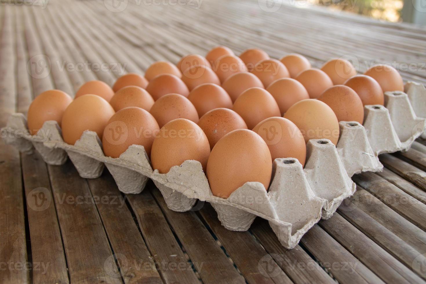 los huevos de gallina marrones están alineados en una bandeja. muchos huevos de gallina marrones están juntos en una bandeja. hay un fondo de bambú. foto