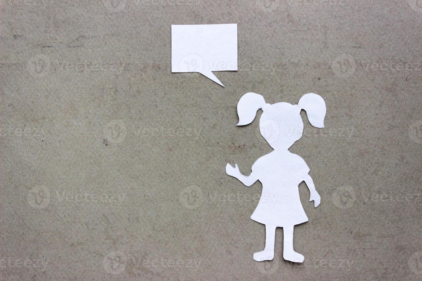 Silhouette of a girl in a dress and with ponytails made of white paper, cut by hand. In right side of the photo. With copy space. On beige background photo