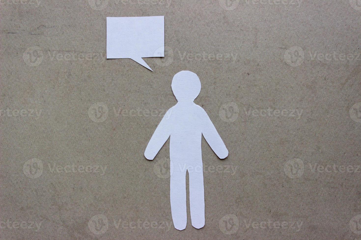 Silhouette of man cut out of white paper. With speech-bubble. In the center of photo on a beige background