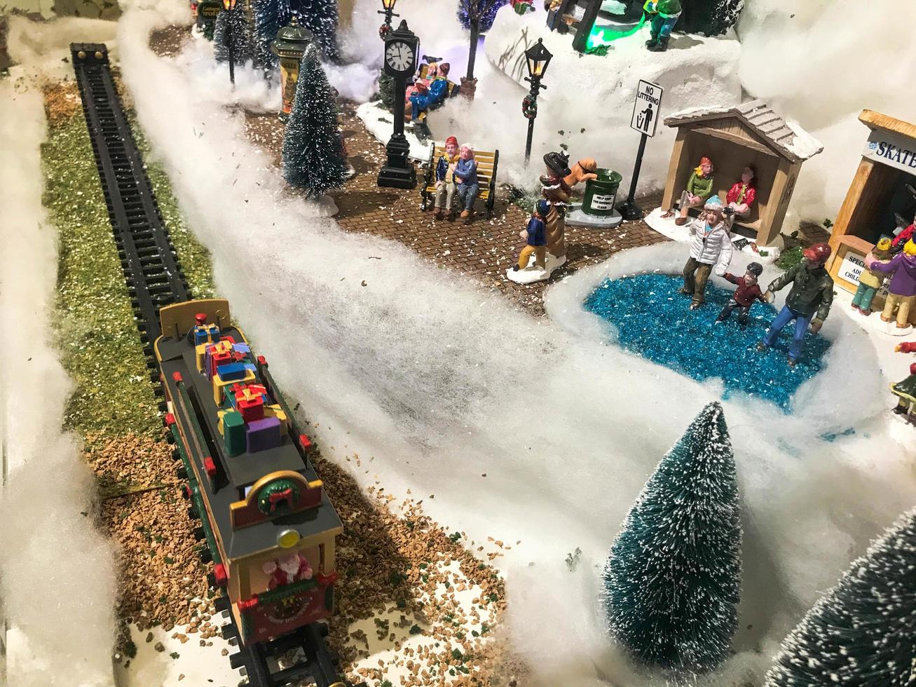paisaje de año nuevo. miniatura de juguete para el escaparate. lindo escaparate, composición hecha a mano. hay un tren en el centro, los vagones están cubiertos de nieve foto