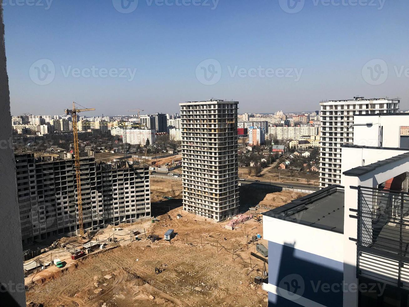 Building with the help of construction cranes of high reinforced concrete, panel, cast-frame, frame-block houses, buildings, skyscrapers, new buildings on the background of sandy land photo