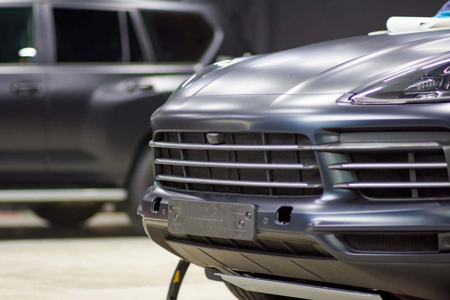 Toyota Land Cruiser and Porsche Cayenne cars covered with a protective matte paint film in black are in the repair shop. PPF polyurethane film protects car paint. Chelyabinsk, Russia, April 03, 2021 photo